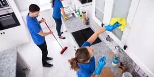 firma sprzątająca składająca się z trzech osób, sprząta kuchnie. Jeden myję szafkę, drugi zamiata, a trzeci myje zlew